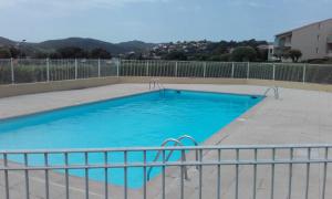 ein großer blauer Swimmingpool mit einem Zaun darum in der Unterkunft appartement vue mer piscines parking LES CORAUX AGAY PLAGE in Agay - Saint Raphael