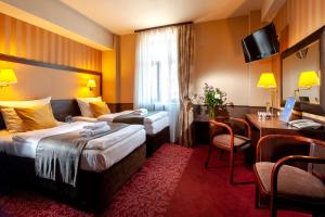 a hotel room with two beds and a desk at Hotel Wielopole in Krakow