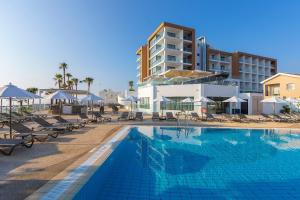 a swimming pool with chairs and a hotel at Leonardo Crystal Cove Hotel & Spa – Adults only in Protaras