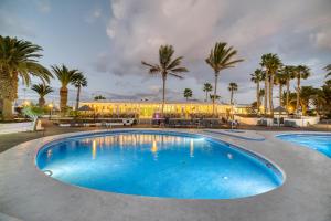 una gran piscina con palmeras y un edificio en Ona Las Brisas, en Playa Blanca