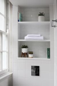 a white tiled bathroom with white shelves with plants at Inhabit Southwick Street, a Member of Design Hotels in London