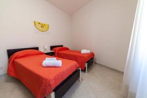 two beds in a room with a clock on the wall at Casa Vacanze Tridente in Trapani