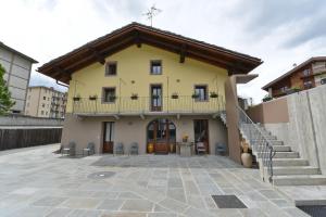 une maison jaune avec un balcon au-dessus dans l'établissement Vecchio Mulino Guest House, à Aoste