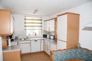 eine Küche mit weißen Schränken und einem Waschbecken in der Unterkunft Ferienwohnungen Richard Wurz in Reichenau