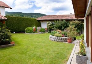 einen Garten eines Hauses mit grünem Gras und Büschen in der Unterkunft Haus Gunda in Arrach