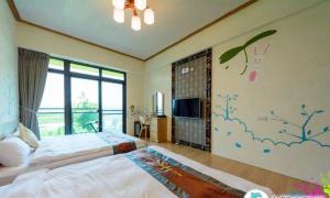 um quarto com uma cama e uma televisão na parede em Yiren Hotel em Hengchun Old Town