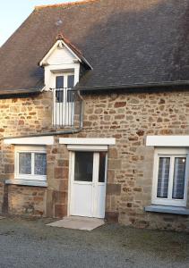 een stenen huis met een witte deur en twee ramen bij le gite du baron in Roz-sur-Couesnon