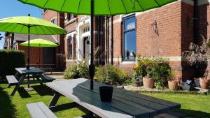 a picnic table with two green umbrellas in a yard at The Mon Fort in Bridlington