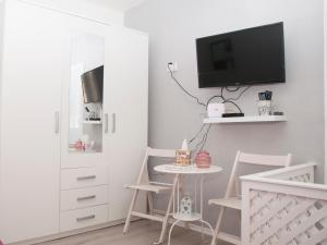 ein Wohnzimmer mit einem TV, einem Tisch und Stühlen in der Unterkunft Bistrik Rose Apartment in Sarajevo