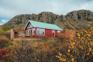 a red house with a mountain in the background at Mulakot Cosy Cabins in Borgarnes