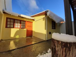 Una casa amarilla con nieve encima. en Meridiano68 Apartment en Ushuaia