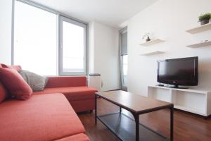 salon z czerwoną kanapą i telewizorem w obiekcie Juls Apartment next to football and hockey stadium w Bratysławie