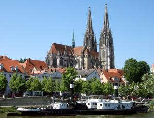 a city with a church and a river with boats at Apartment Beethoven in Regensburg