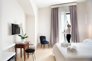 a woman standing in a hotel room looking out the window at I Bastioni San Domenico - Boutique Hotel in Gallipoli