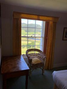 a bedroom with a chair and a window with a view at Craignuisq Farmhouse in Pitlochry