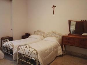 um quarto com duas camas e uma cruz na parede em Villa Sacro Cuore em San Giovanni Rotondo