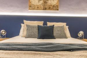 um quarto com uma cama com almofadas e uma parede azul em Pregiata camera con bagno privato - Blu di Prussia em Trieste