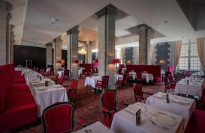 un comedor con mesas blancas y sillas rojas en Royal Hainaut Spa & Resort Hotel en Valenciennes