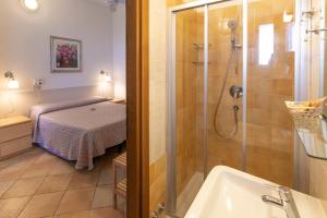 ein Bad mit einer Dusche, einer Badewanne und einem Bett in der Unterkunft Villa Rosy in Torre del Lago Puccini