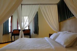 ein Schlafzimmer mit einem Bett mit Vorhängen und einem Klavier in der Unterkunft Mom's Corner in Malang