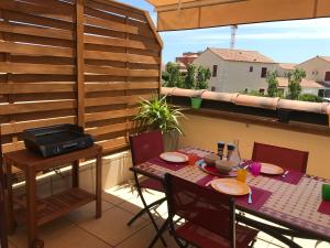 a patio with a table and chairs on a balcony at Grandes Bleues, Appartement T3 duplex, piscine, Narbonne Plage in Narbonne-Plage
