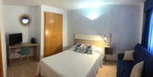ein Schlafzimmer mit einem weißen Bett und einem blauen Sofa in der Unterkunft Hotel Valldigna in Tavernes de la Valldigna