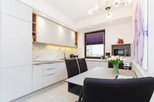 a kitchen with white cabinets and a table and chairs at Apartments Kraków Przedwiośnie by Renters in Krakow