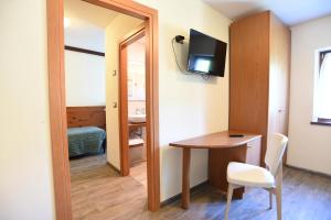 Cette chambre dispose d'une table, d'un miroir et d'un bureau. dans l'établissement Albergo Bucaneve, à Pievepelago