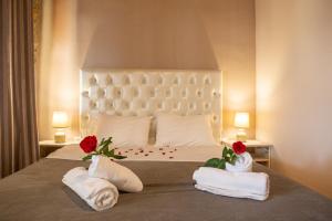 1 dormitorio con 1 cama con 2 toallas y 2 rosas en To Archontiko tis Nikis, en Ioannina