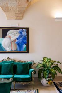 a living room with a green couch and a painting at I Bastioni San Domenico - Boutique Hotel in Gallipoli