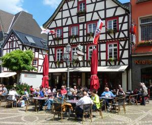 grupa ludzi siedzących przy stołach przed budynkiem w obiekcie Ferienhaus Schlupfwinkel w mieście Bad Neuenahr-Ahrweiler