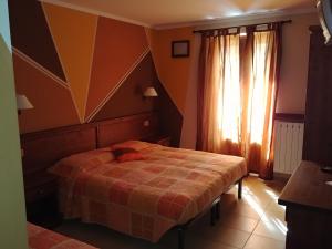 a bedroom with a bed and a window with curtains at CHALET SEGGIOVIA in Pontechianale