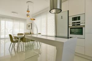 eine weiße Küche mit einer Theke und einigen Stühlen in der Unterkunft Casa Mazal, Lujosa villa Independiente a 150m del mar in Pilar de la Horadada