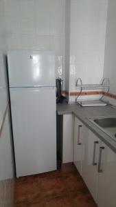 eine Küche mit einem weißen Kühlschrank und einer Spüle in der Unterkunft Calle Rubiños, 23 Apartamento in Sanlúcar de Barrameda
