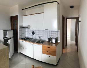 una cucina con armadi bianchi e lavandino di Villa Barabarca a Capoliveri