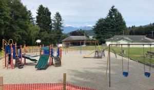 a playground with slides and swings in a park at Gibsons Harbour Retreat in Gibsons