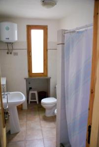 a bathroom with a toilet and a sink and a window at Valledoria holiday flats in Valledoria