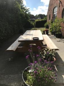 a wooden picnic table in a garden with flowers at Theaterwerkplaats private appartment in Kantens