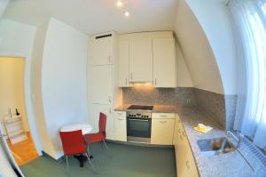 a small kitchen with white cabinets and red chairs at Spacious 2-bedroom near lake - Stardust 32 in Zurich