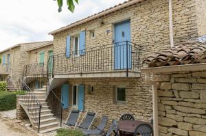 una casa de piedra con una escalera y sillas delante de ella en Gordes Le Bastidon, en Gordes