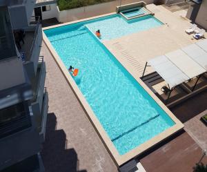 an overhead view of a swimming pool with two people in it at ARENA PLAZA DEPARTAMENTO PLAYA con vista al mar in Tonsupa