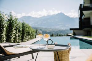 a table with two wine glasses and a mirror on it at Garni-Hotel Der Forsterhof in Lagundo