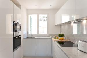 a white kitchen with white cabinets and a window at Superbe T3 sur la Marina de Bonifacio in Bonifacio