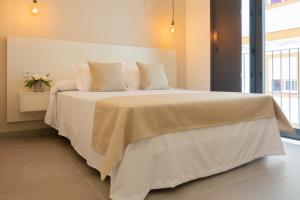 a bedroom with a large bed with white sheets and pillows at La Mina Hostal Boutique in Conil de la Frontera