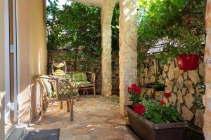 un patio con sillas y flores y una pared de piedra en Apartment Limun en Ližnjan