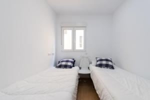 two beds in a room with white walls at VISTA PLAYA Y MAR - sea view, wifi and AC in Melenara