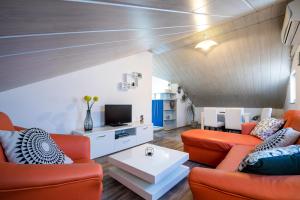 un soggiorno con 2 divani arancioni e una TV di Apartment Adriana a Vela Luka (Vallegrande)