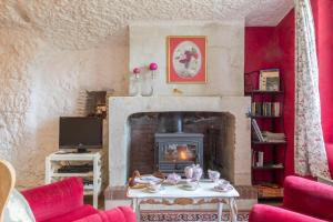 a living room with a fireplace with a table and a fire place at Gîte De La Rochère in Noizay