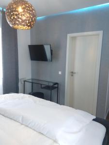 a bedroom with a bed and a television and a chandelier at Hotel am Stadion VANINO cucina ITALIAN in Bielefeld