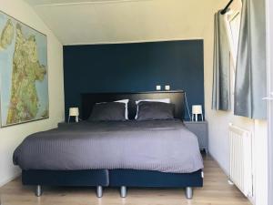 een slaapkamer met een groot bed met een blauwe muur bij chalet hensbroek in Hensbroek